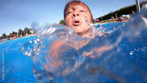 Selfie stick point of view boy diving underwater and gesturing peace sign