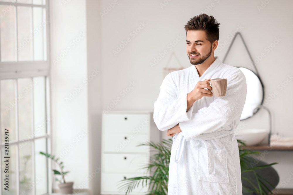 Fototapeta premium Handsome young man drinking tea in bathroom