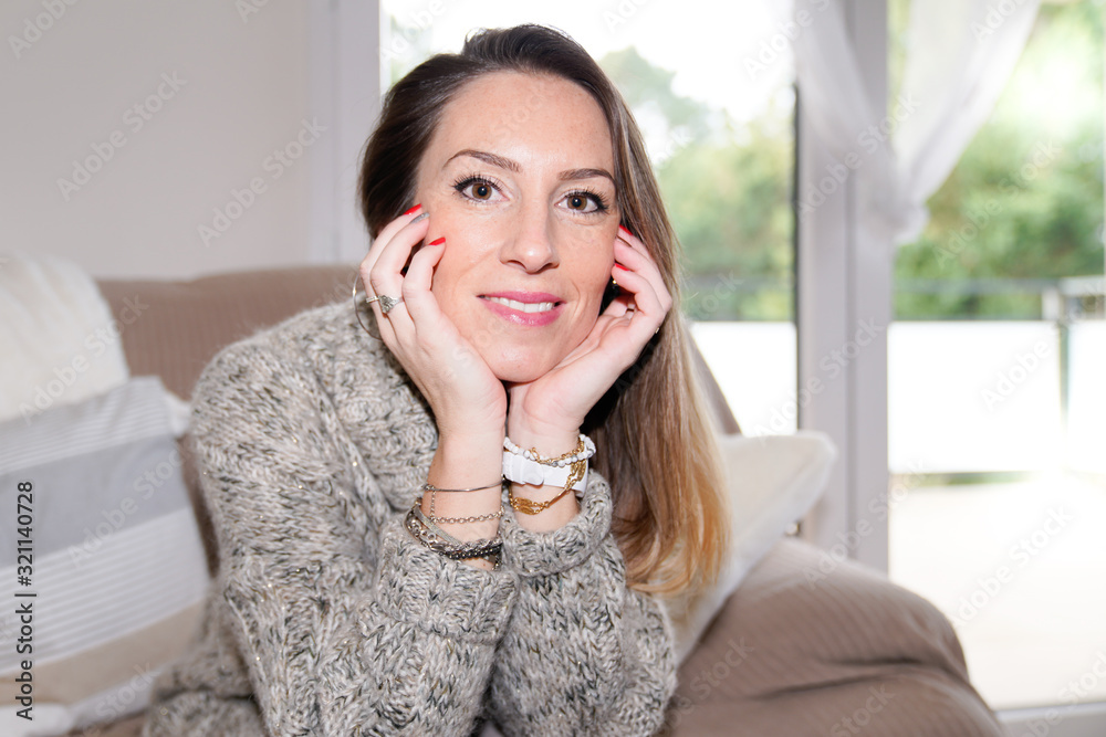 Happy beauty woman resting comfortably sitting on brown sofa in living room at home Happy beauty woman resting comfortably sitting on brown sofa in living room at home