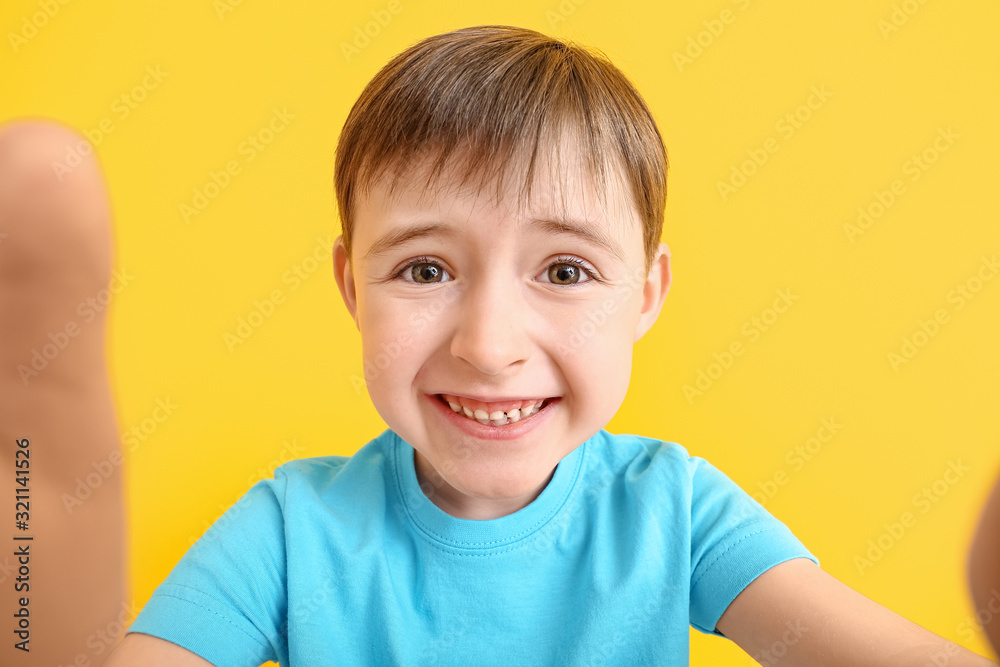 Happy smiling little boy taking selfie on color background Happy smiling little boy taking selfie on color background