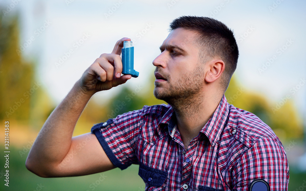 Fototapeta premium Young man treating asthma with inhaler
