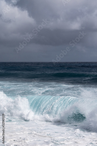 Kaimu Beach  Hawaii  USA. - January 14  2020  Portrait of Dark ocean under heavy gray rain cloudscape produces white surf when azure wave turns and crashes.