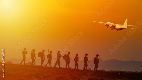 Silhouette of military rangers and Helicopter with soldier on the top of mountain at sunset 