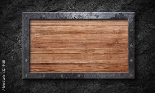 Old wooden sign with metal frame rock wall background