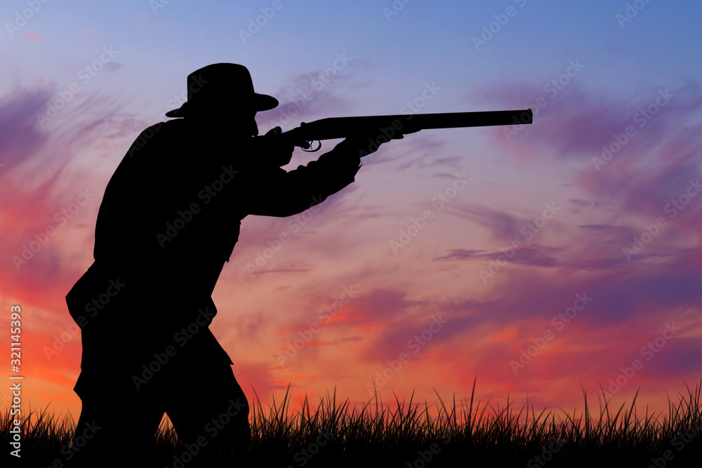 Silhouette of a hunter with a gun in the reeds against the sun, an ambush for ducks with dogs Silhouette of a hunter with a gun in the reeds against the sun, an ambush for ducks with dogs