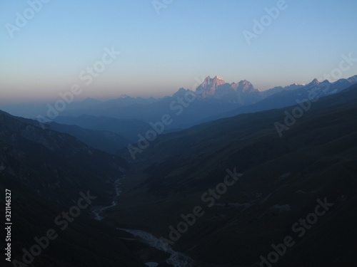 Mountain landscape of Svaneti on bright summer sunny day. Mountain lake  hills covered green grass on snowy rocky mountains background. Caucasus peaks in Georgia. Amazing view on wild georgian nature