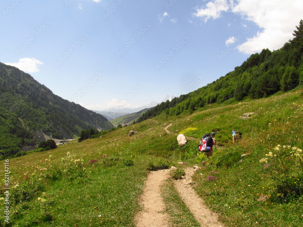 Mountain landscape of Svaneti on bright summer sunny day. Mountain lake, hills covered green grass on snowy rocky mountains background. Caucasus peaks in Georgia. Amazing view on wild georgian nature Mountain landscape of Svaneti on bright summer sunny day. Mountain lake, hills covered green grass on snowy rocky mountains background. Caucasus peaks in Georgia. Amazing view on wild georgian nature