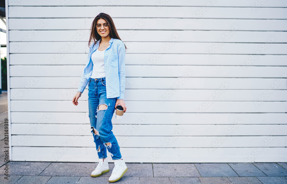 Full length portrait of attractive hipster girl in trendy outfit enjoying free time in city posing near copy space area for advertising,cheerful young woman in jeans apparel looking at camera outdoors Full length portrait of attractive hipster girl in trendy outfit enjoying free time in city posing near copy space area for advertising,cheerful young woman in jeans apparel looking at camera outdoors