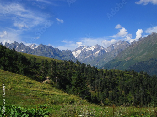 Mountain landscape of Svaneti on bright summer sunny day. Mountain lake, hills covered green grass on snowy rocky mountains background. Caucasus peaks in Georgia. Amazing view on wild georgian nature © nika