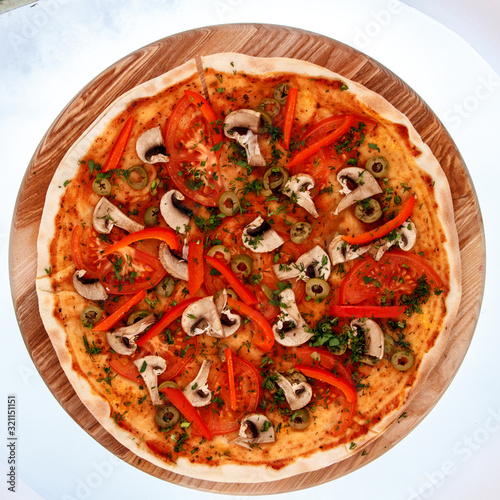 Pitzza with mushrooms on a wooden plate.