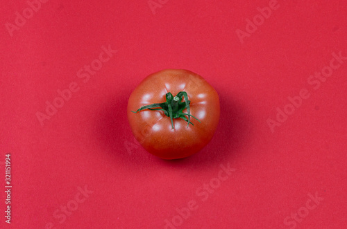 Top view and flat lay photo with one red natural eco tomato on the red solid background © Artur Falgowski