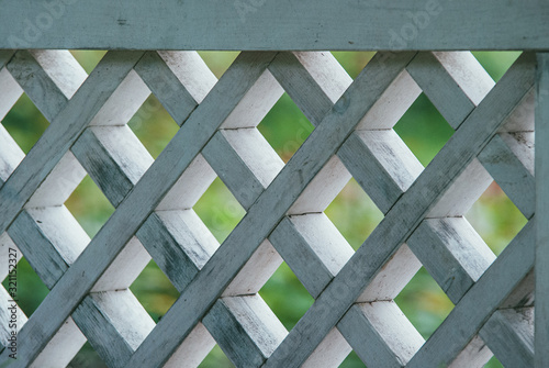 diamond-shaped wooden lattice painted white against the background of a green lawn