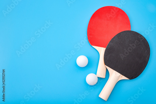 Pingpong lesson and winning competitive challenge concept with red and black table tennis or ping pong paddle isolated on blue background with copy space