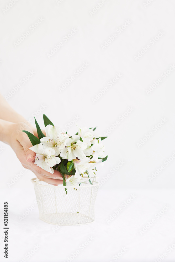 Woman puts white flowers into the basket