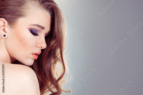 Beautiful woman portrait in side profile. Beauty Spa girl with perfect fresh skin. Pure blonde model holiday makeup curly hair posing isolated light gray wall. Youth Skin Care Concept Studio shot