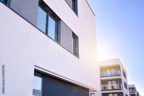 Modern multi story building being lit by the setting sun at afternoon. New apartment house residential building outdoor concept.