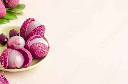 peeled ripe exotic tropical lychee cut-out fruit, with pulp, in shell, with seeds, green leaves on yellow background closeup, copy place for text. soft focus