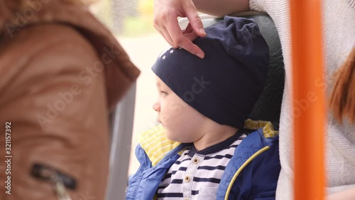 Young mother and little son ride on a bus through city during sunny day. 4K