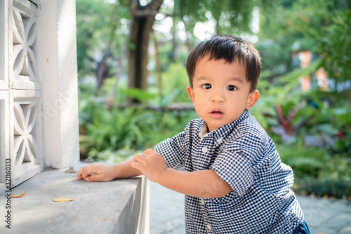 Adorable baby boy toddler walking in garden hpme green tree photo