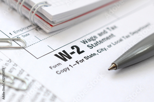 The pen and notebook on the tax form W-2 Wage and Tax Statement. The time to pay taxes