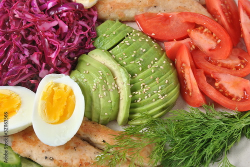 Chicken salad with avocado , tomatoes, red cabbage, cucumbers, boiled eggs and parsley. Healthy lunch bowl with vegetables and chicken on wooden background Healthy food concept photo