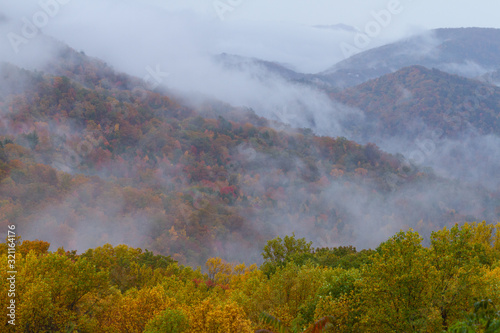 Morning fog rises over fall foliage in The Great Smoky Mountains National Park.