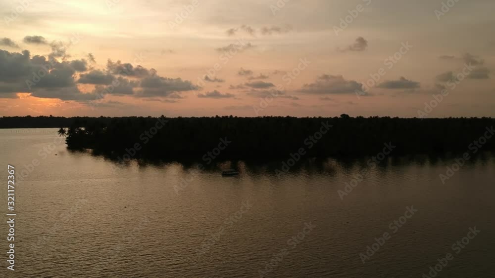 Beautiful aerial shot of a backwater Vembanadu Lake,water lines,twilight sunset,coconut trees ,water transportation,clouds,reflation,House boat,sun down Beautiful aerial shot of a backwater Vembanadu Lake,water lines,twilight sunset,coconut trees ,water transportation,clouds,reflation,House boat,sun down