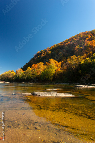 The crystal clear Water of the  Potomac River in Harper's Ferry, West Virginia, on a sunny Day with colorful Foliage on Trees