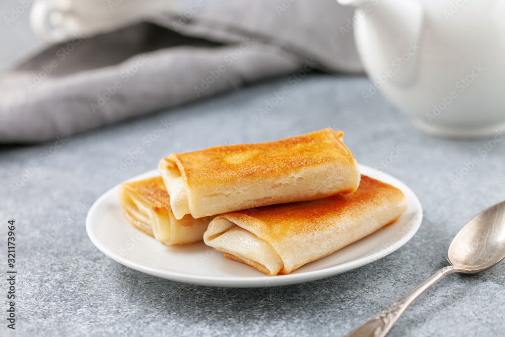 Pancakes envelopes with curd or ricotta in a plate on a grey background Pancakes envelopes with curd or ricotta in a plate on a grey background