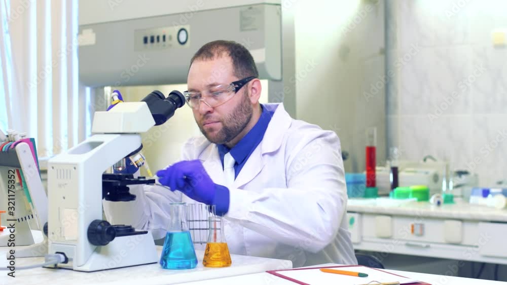 Chemist. A scientist conducts experiments in a scientific laboratory. Performs research using a microscope. Eureka. Victory. New discovery. Happy scientist. Chemist. A scientist conducts experiments in a scientific laboratory. Performs research using a microscope. Eureka. Victory. New discovery. Happy scientist.