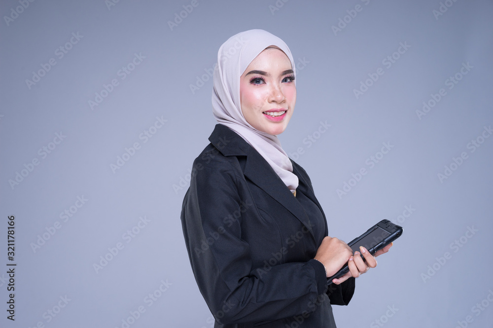 Half length portrait of an attractive Muslim businesswoman wearing hijab with tablet and gestures isolated on grey background. For image cutout for corporate, technology, business or finance. Half length portrait of an attractive Muslim businesswoman wearing hijab with tablet and gestures isolated on grey background. For image cutout for corporate, technology, business or finance.