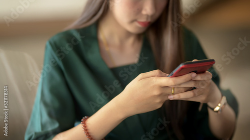 Cropped shot of businesswoman using smartphone in blurred simple office room background © bongkarn