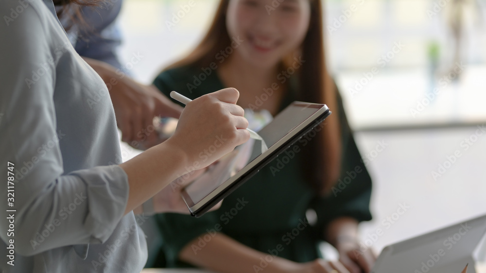 Cropped shot of professional designer team using digital tablet in simple co working space Cropped shot of professional designer team using digital tablet in simple co working space