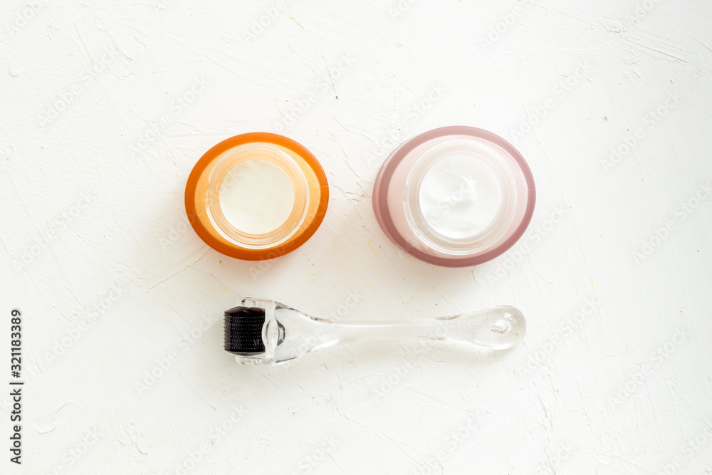 Dermaroller for mesotherapy near creams on white background top-down flat lay Dermaroller for mesotherapy near creams on white background top-down flat lay