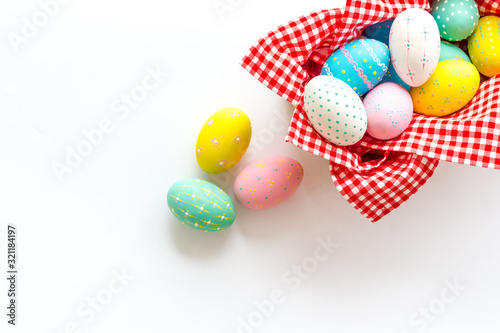 Easter eggs painted in basket on white desk top-down copy space