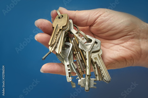 Woman's hand holding a bunch of keys on a blue background