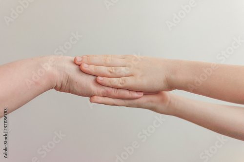 adult holding a baby hand over white wall background