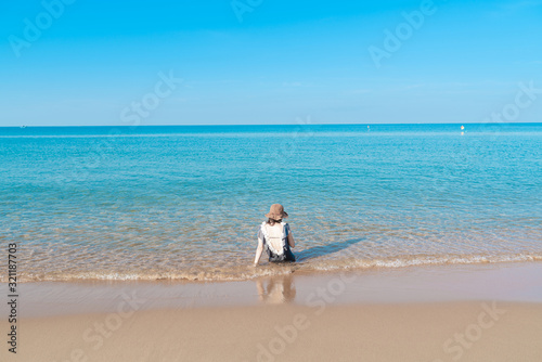 Tropical sea beach with young girl relaxing on sand