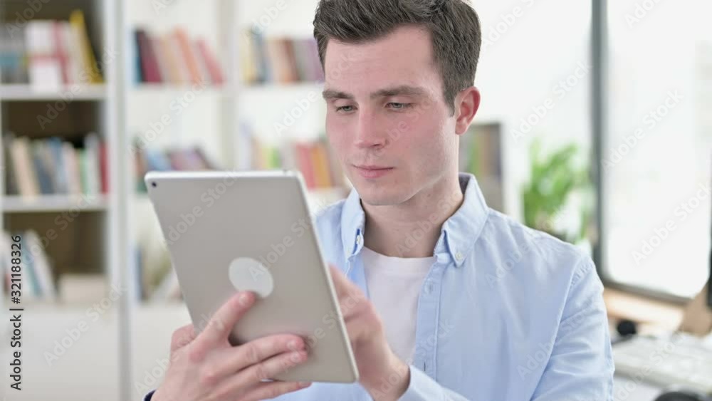 Cheerful Young Man using Tablet PC Cheerful Young Man using Tablet PC