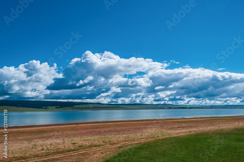 white clouds in the blue sky float over the lake