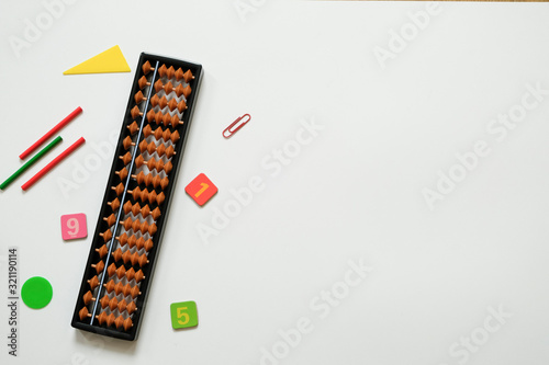 Mental arithmetic and math concept: colorful pens and pencils, numbers, abacus scores on white background, copy space photo