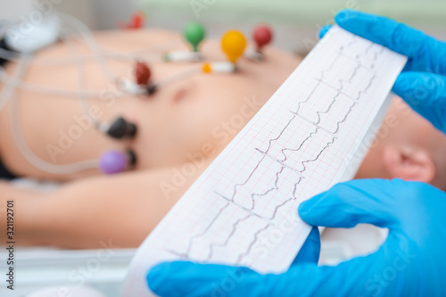 Heart cardiogram in the hands of a doctor close-up. Cardiologist is studying the testimony of an electrocardiograph. photo