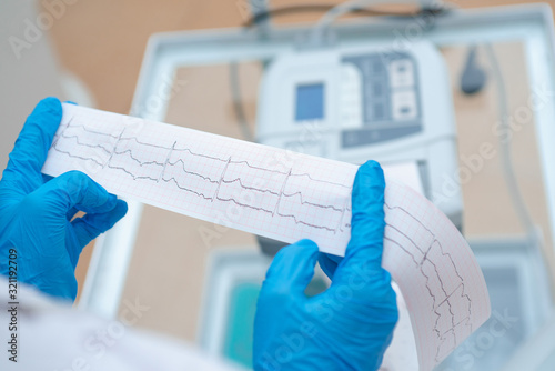 Heart cardiogram in the hands of a doctor close-up. Cardiologist is studying the testimony of an electrocardiograph.
