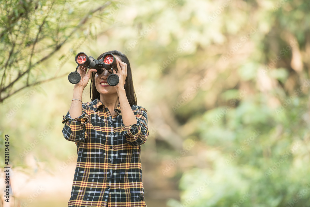 hiking women use binoculars to travel and have a happy smile. tourist looking through binoculars considers wild birds in the jungle. bird watching tours. with backpack. travel concept hiking women use binoculars to travel and have a happy smile. tourist looking through binoculars considers wild birds in the jungle. bird watching tours. with backpack. travel concept