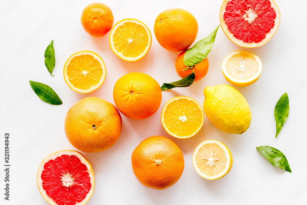 Fresh citrus background. Oranges, grapefruits, leaves - whole fruits and halfs - on white background top-down Fresh citrus background. Oranges, grapefruits, leaves - whole fruits and halfs - on white background top-down