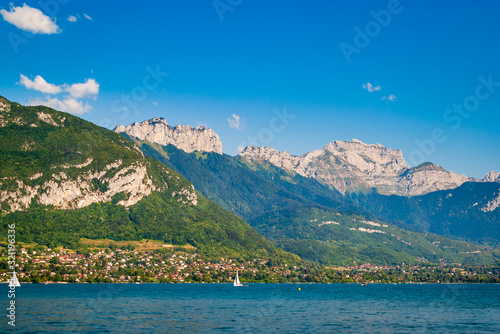 A summer view of the beautiful French Lake Annecy with its turquoise crystal clear waters surrounded by stunning mountains, Savoy, France.