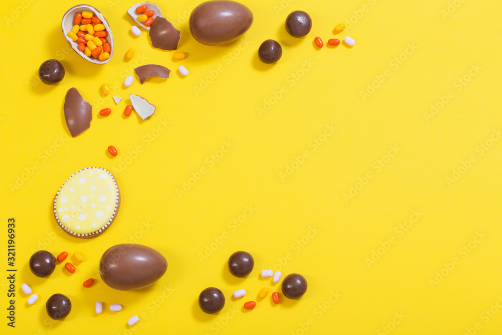 Easter yellow background with chocolatte eggs and candy Easter yellow background with chocolatte eggs and candy