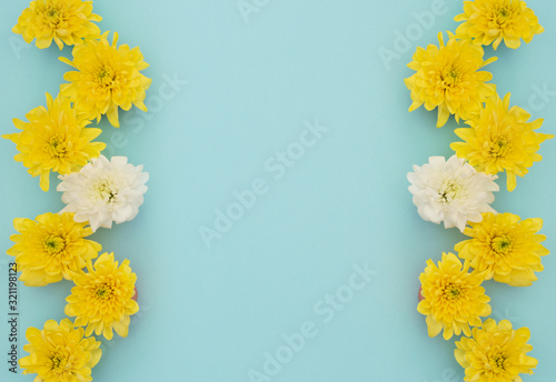 Yellow and white flowers on blue background. Mother’s Day, Spring concept. Greeting, invitation card. Flat lay, top view style with copy space for your text.