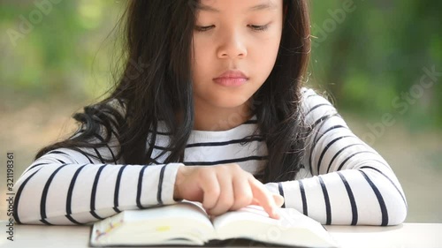 cute little asian girl in reading bible. hands holding on a holy bible. little child girl hands folded in prayer on a holy Bible for faith,spirituality and religion concept.