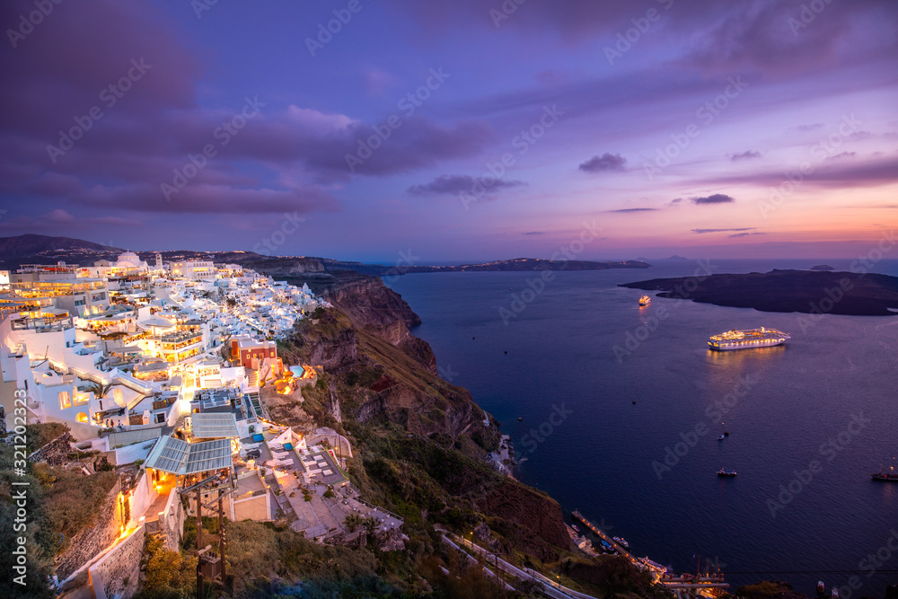 Fantastic summer landscape in famous travel destination. Luxury vacation. Amazing evening view of Fira, caldera, volcano of Santorini, Greece with cruise ships at sunset. Cloudy dramatic sky